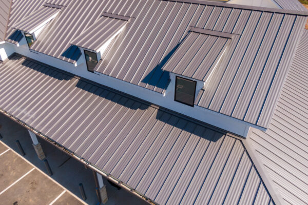 Drone aerial photos showcasing commercial buildings with sleek standing seam metal roofs. The images highlight the reflective steel panels, clean architectural lines, and durable construction used in contemporary retail and industrial facilities. Captured under bright sunlight, emphasizing the modern design and energy efficiency of metal roofing systems.